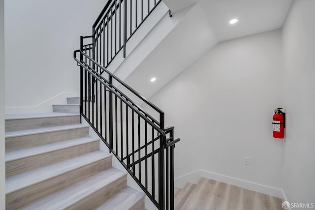 staircase featuring recessed lighting, wood finished floors, and baseboards