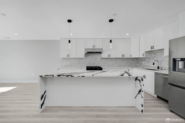 kitchen with under cabinet range hood, stainless steel appliances, a sink, a center island, and tasteful backsplash