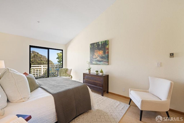 bedroom with light wood-type flooring, vaulted ceiling, baseboards, and access to exterior