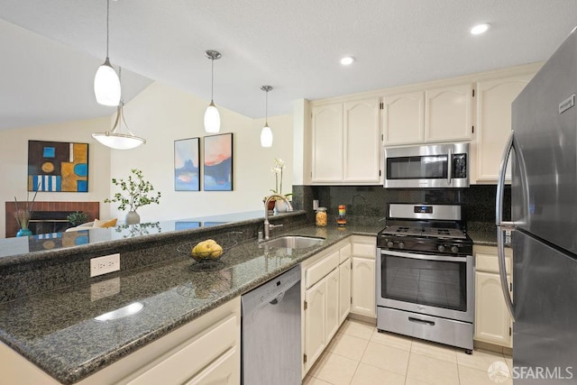kitchen featuring stainless steel appliances, vaulted ceiling, light tile patterned floors, a sink, and a peninsula