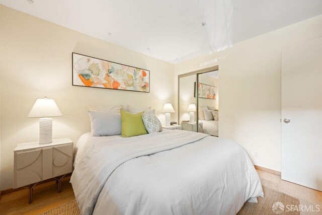 bedroom with light wood finished floors and a closet