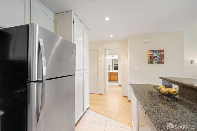 kitchen featuring white cabinets, recessed lighting, dark stone countertops, light tile patterned floors, and freestanding refrigerator