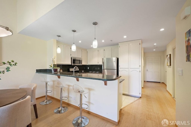 kitchen featuring a peninsula, light wood finished floors, appliances with stainless steel finishes, and recessed lighting
