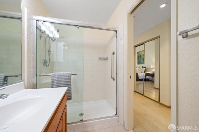 bathroom with connected bathroom, vanity, wood finished floors, and a stall shower