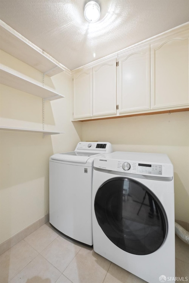 clothes washing area with baseboards, cabinet space, washer and clothes dryer, and light tile patterned flooring
