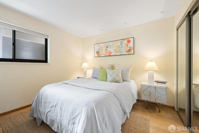 bedroom featuring baseboards, wood finished floors, and a closet