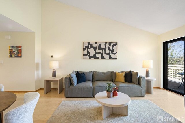 living area with light wood-style flooring, baseboards, and high vaulted ceiling