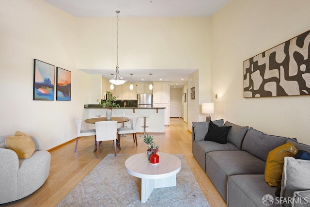 living area featuring baseboards, a high ceiling, and light wood-type flooring