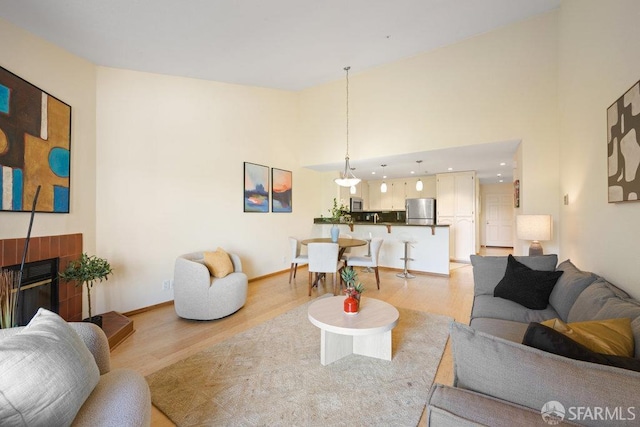living area featuring baseboards, a high ceiling, and light wood-style floors
