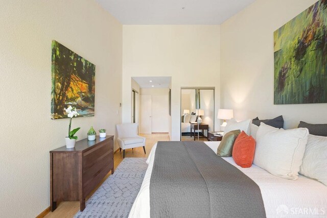 bedroom with a towering ceiling and wood finished floors