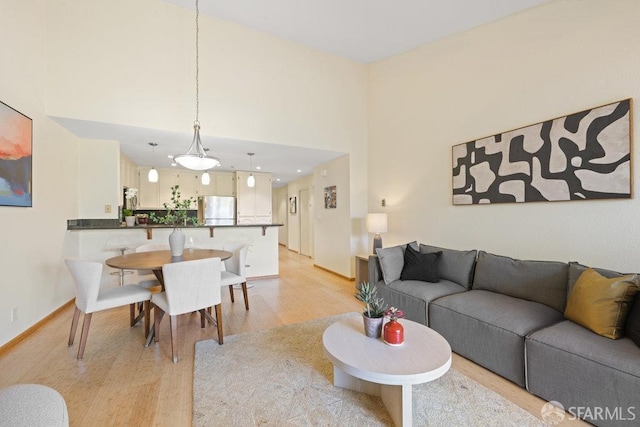 living area with light wood finished floors, a towering ceiling, and baseboards