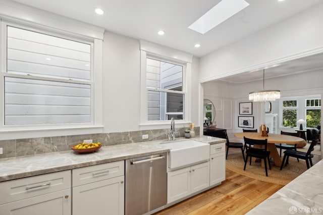 1982 Fell St, San Francisco, CA 94117 - kitchen featuring dishwasher, a sink, light wood-style floors, white cabinets, and light stone counters