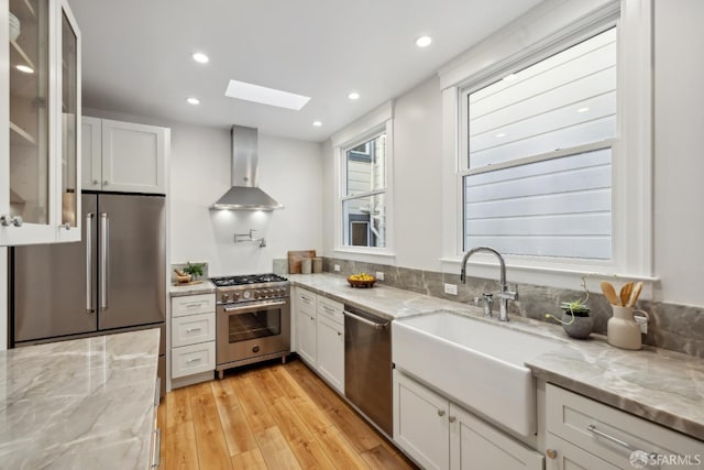 1982 Fell St, San Francisco, CA 94117 - kitchen featuring wall chimney range hood, appliances with stainless steel finishes, a skylight, a sink, and light wood-style flooring