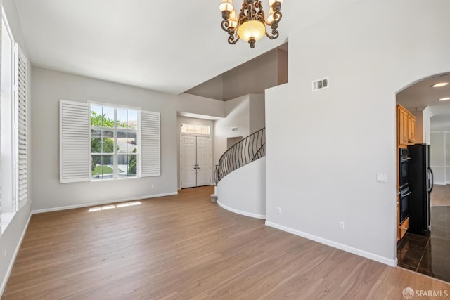 5317 Judsonville Dr, Antioch, CA 94531 - unfurnished living room featuring light wood-style flooring, baseboards, arched walkways, and a towering ceiling