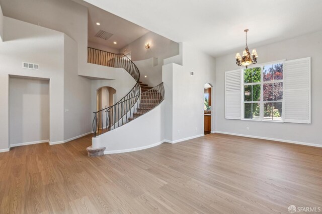 5317 Judsonville Dr, Antioch, CA 94531 - unfurnished living room featuring arched walkways, stairway, a high ceiling, a chandelier, and wood finished floors