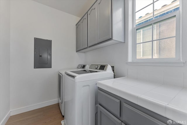 washroom with electric panel, a healthy amount of sunlight, cabinets, and washer and clothes dryer