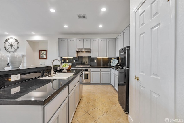 kitchen featuring gray cabinets, stainless steel appliances, light tile patterned floors, decorative backsplash, and sink