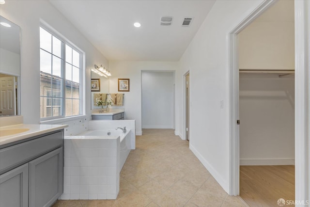 bathroom featuring vanity, tile patterned floors, and a tub to relax in