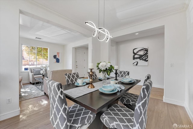 dining area with light hardwood / wood-style floors and crown molding