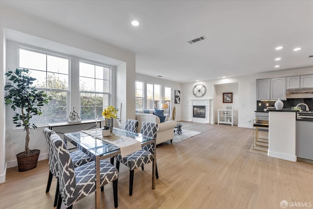 dining space with sink, light hardwood / wood-style flooring, and plenty of natural light