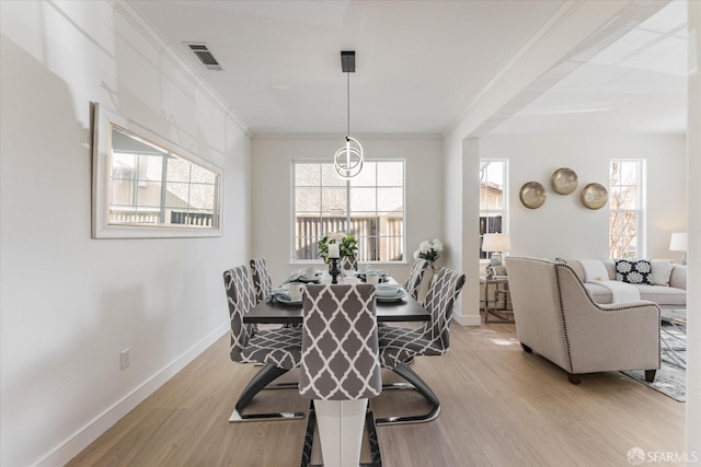 dining room with ornamental molding and light hardwood / wood-style floors