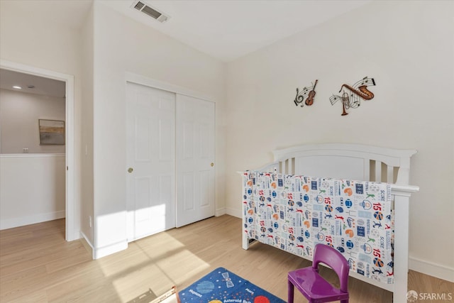 bedroom featuring a nursery area, a closet, and hardwood / wood-style flooring