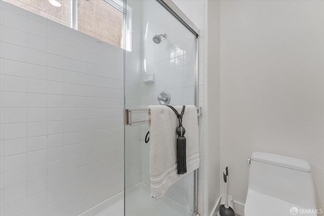 bathroom featuring a shower with shower door and toilet