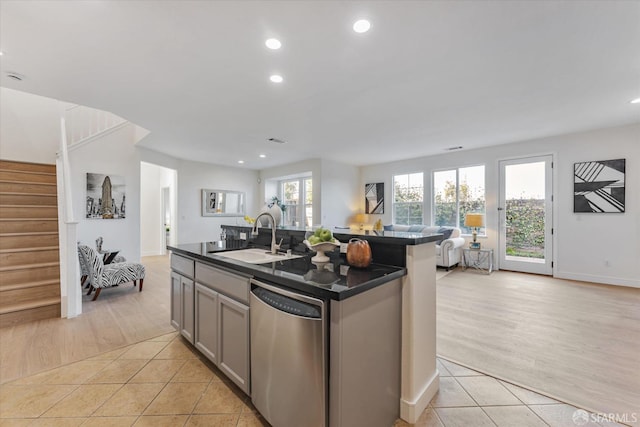 kitchen with dishwasher, a kitchen island with sink, gray cabinets, light tile patterned floors, and sink