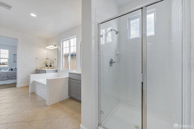 bathroom featuring plus walk in shower, tile patterned flooring, a wealth of natural light, and vanity