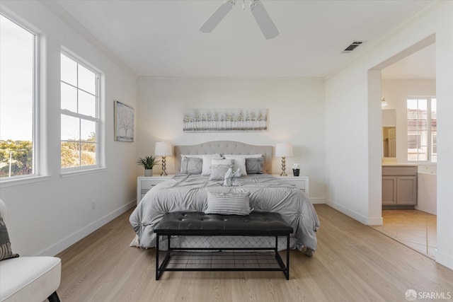 bedroom featuring ensuite bathroom, ceiling fan, light hardwood / wood-style floors, and multiple windows