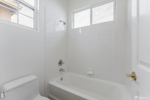 bathroom featuring toilet,  shower combination, and a healthy amount of sunlight