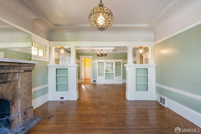 foyer featuring an inviting chandelier, dark hardwood / wood-style flooring, a brick fireplace, and ornate columns