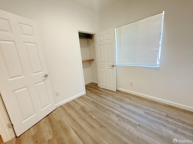 unfurnished bedroom featuring a closet, a spacious closet, and light hardwood / wood-style flooring