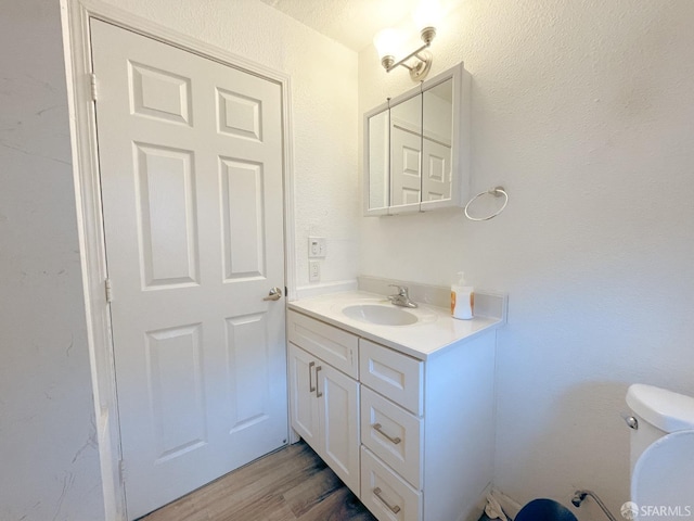 bathroom featuring vanity, wood-type flooring, and toilet