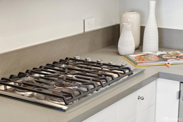 room details featuring white cabinetry, stainless steel gas stovetop, and tasteful backsplash