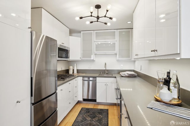 kitchen featuring sink, stainless steel appliances, white cabinetry, and light hardwood / wood-style flooring