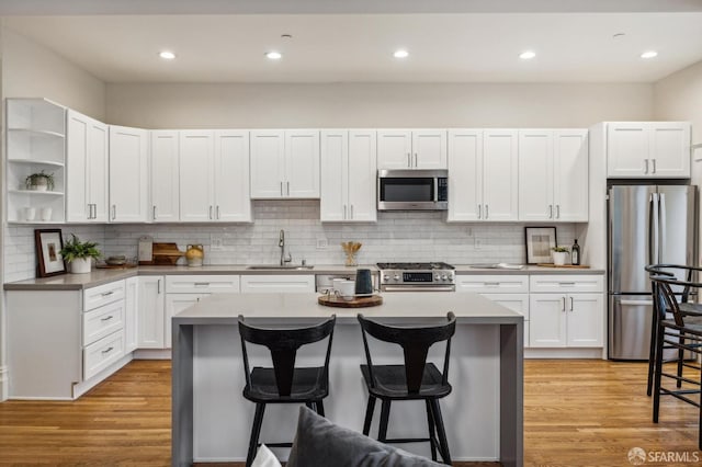 kitchen featuring sink, a kitchen island, a kitchen bar, white cabinetry, and stainless steel appliances