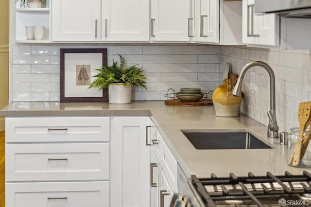 kitchen featuring decorative backsplash, white cabinetry, and sink