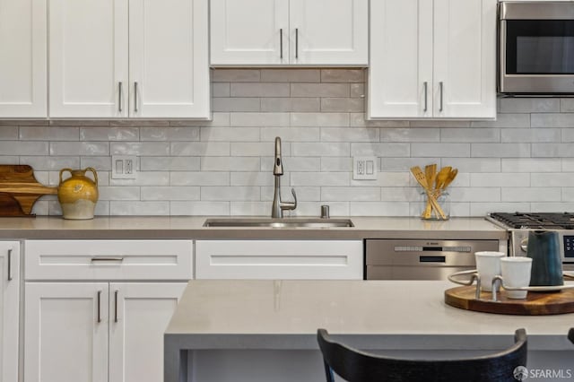 kitchen with white cabinets, sink, appliances with stainless steel finishes, and tasteful backsplash