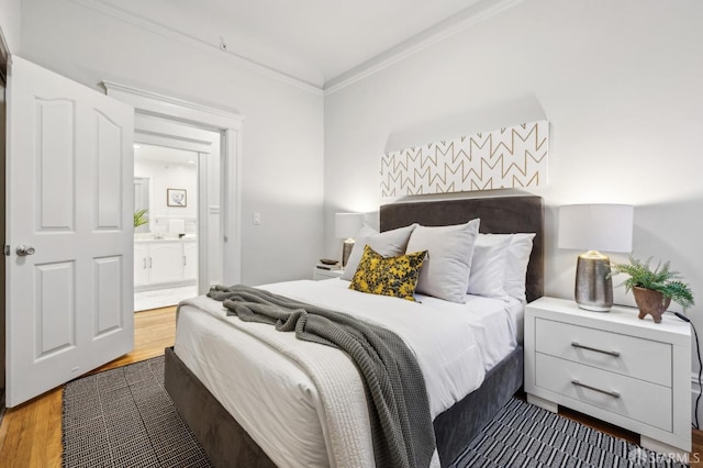 bedroom featuring hardwood / wood-style flooring, ensuite bathroom, and crown molding