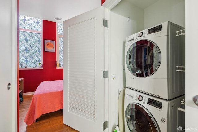 laundry room with hardwood / wood-style flooring and stacked washer / dryer