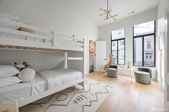 bedroom with vaulted ceiling, a chandelier, and light wood-type flooring