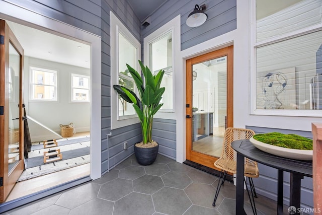 doorway featuring dark tile patterned floors and wooden walls