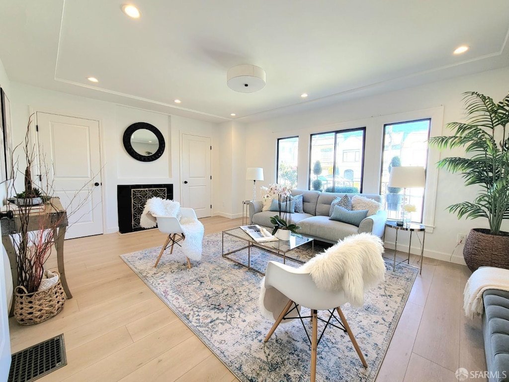 living area featuring light wood finished floors, baseboards, visible vents, a fireplace, and recessed lighting