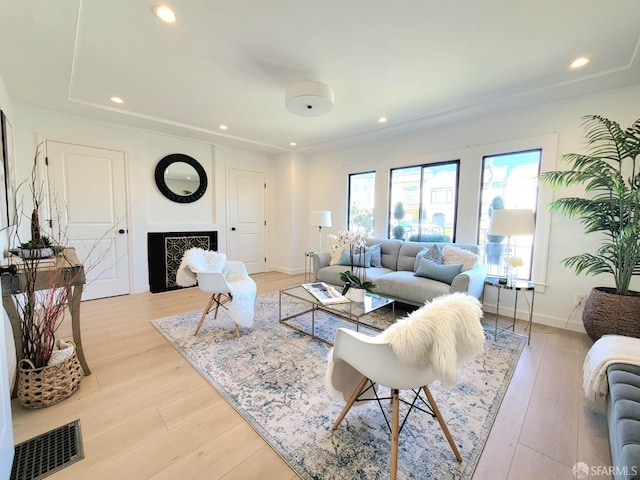 living area featuring light wood finished floors, baseboards, visible vents, a fireplace, and recessed lighting