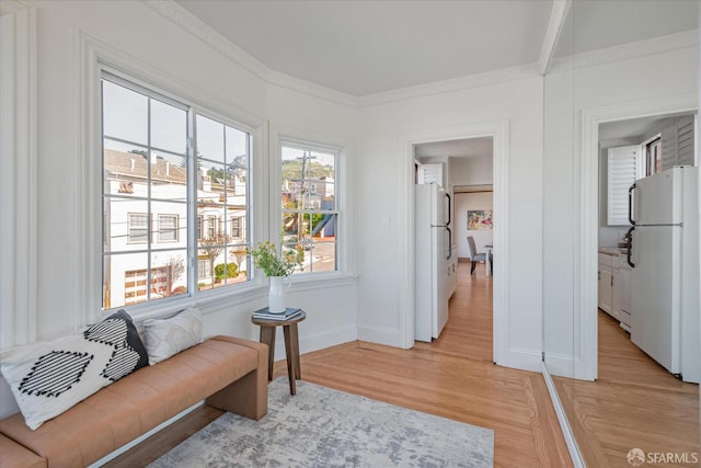 living area with ornamental molding, baseboards, and light wood finished floors