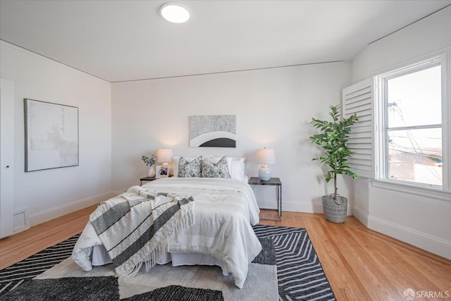 bedroom with visible vents, baseboards, and wood finished floors