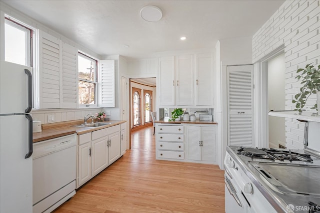 kitchen with recessed lighting, white appliances, a sink, white cabinets, and light wood-type flooring