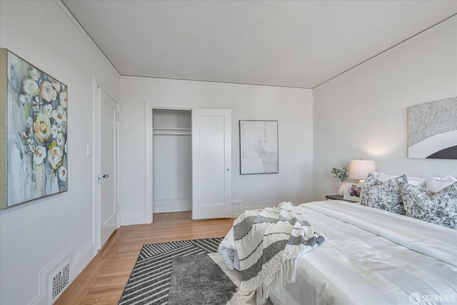 bedroom with a closet, light wood-type flooring, visible vents, and baseboards