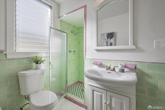 bathroom with toilet, a wainscoted wall, vanity, tile walls, and a shower stall